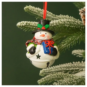 Detailed view of snowman Christmas bell ornament hanging on a snowy pine tree branch