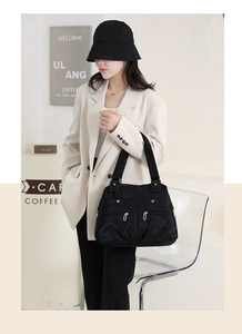 Close-up of black nylon tote bag with dual front zippers and wide shoulder strap