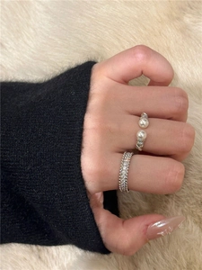 Close-up of minimalist silver rings with pearls and zircons worn on model's fingers