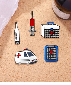 Detailed view of five medical enamel pins including ambulance and syringe with rhinestones