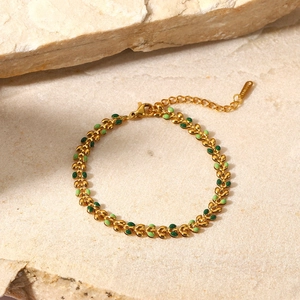 Close-up of 18K gold olive leaf bracelet with green enamel and S.STEEL engraved tag