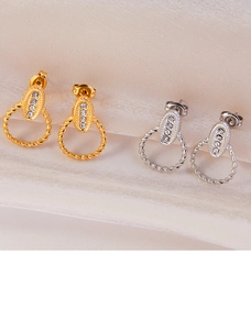 Detail of twisted gold and silver hoop earrings with a sparkling zircon center panel