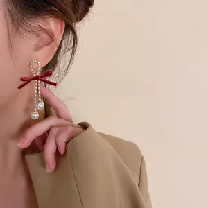 Dettaglio degli orecchini a fiocco in velluto rosso con strass e perle su modella
