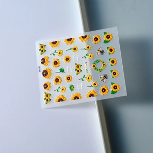 Detail of 3D sunflower nail stickers with bees and embossed floral patterns on white surface