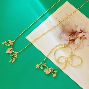Macro view of gold beaded necklaces featuring micro-pave boy, girl, and heart pendants