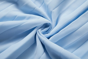 Gros plan sur le tissu mousseline plissé bleu ciel avec plis élégants et texture fine