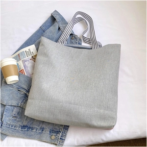 Detailed view of gray jacquard canvas tote bag with striped handles on lifestyle background