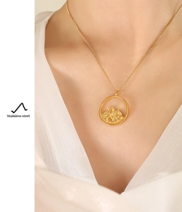 Macro view of golden stainless steel necklace with round mountain relief pendant