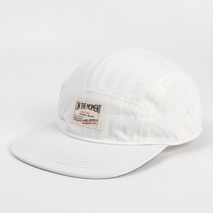 Dettaglio cappello 5-panel bianco con texture in tela di cotone e toppa vintage