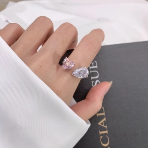 Vue détaillée d'une bague argentée avec cœur rose et pierre en forme de goutte.