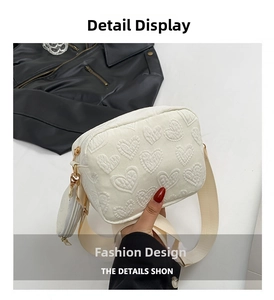 Detail of white embossed heart pattern on crossbody bag with a wide shoulder strap