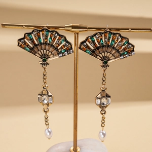 Dettaglio macro di orecchini vintage a ventaglio con strass e perle bianche