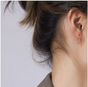 Close-up of a silver water drop geometric ear hook on a female model's ear