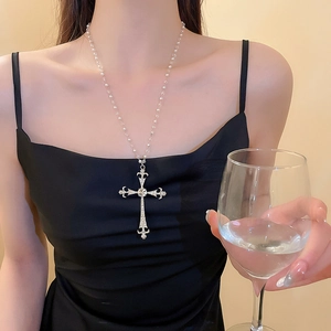 Collana chic con ciondolo a croce d'argento e perle bianche indossata da una modella