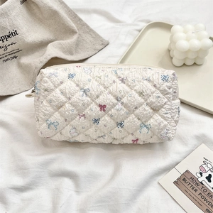 Detailed view of quilted makeup bag featuring colorful cartoon bow and rabbit patterns