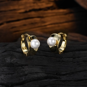 Elegant gold pearl hoop earrings shown on a rustic wooden surface in high detail