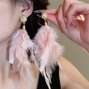 Close-up of pink feather drop earrings with gold spiral base and white pearl accent