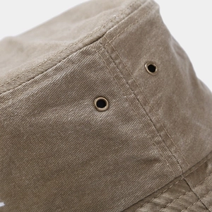 Close-up of earth tone washed canvas bucket hat with bronze eyelets and durable stitching