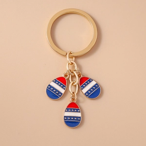 Detail of gold metal keychain with red, white, and blue striped star enamel egg pendants
