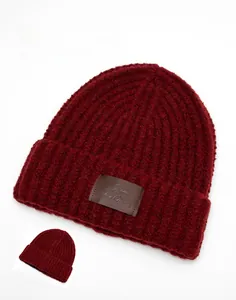Detail of burgundy knit beanie showing thick texture and leather patch for warmth