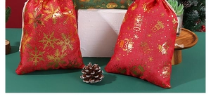 Detail of red and green linen Christmas drawstring bags with gold snowflake patterns