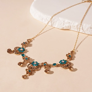 Close-up of vintage gold necklace with blue and amber crystals in a floral design