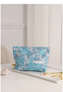 Detail view of blue floral jacquard makeup bag with brand label on elegant tray