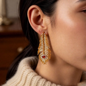 Detail of vintage feather drop earring with orange crystals and a red gemstone focal point