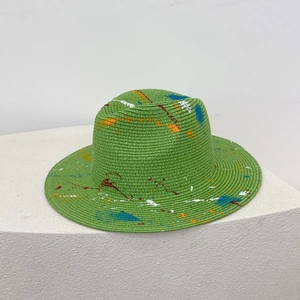 Detail of green straw Panama hat with artistic colorful spray paint splatter design