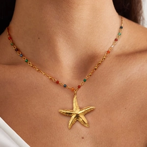 Detail of a gold starfish pendant necklace with colorful beads on a fine chain