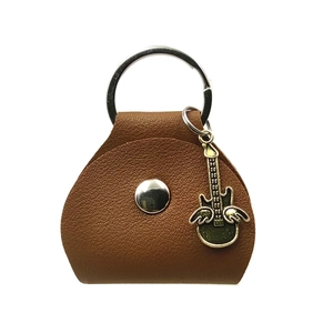 Macro shot of brown leather guitar pick case with silver button and wing charm