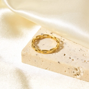 Detail view of 18K gold plated oval chain ring on elegant travertine and silk background