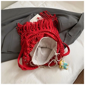 Detail of red handmade woven cotton tote bag with fringe tassels and doll charm