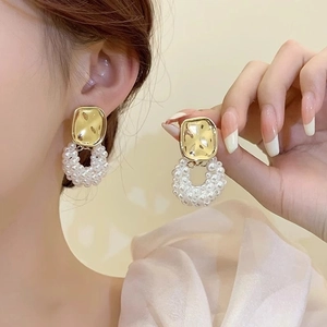 Détail de pétales de fleurs dorés vintage et boucle d'oreille perle sur l'oreille