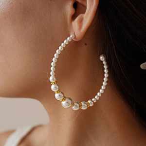 Detail of vintage C-shaped gold hoop earring with pearls on a model's ear
