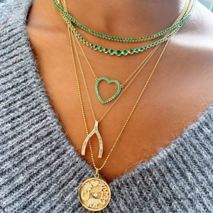 Gros plan sur cinq colliers superposés en plaqué or 18 carats avec chaînes tennis et pendentifs