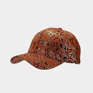 Dettaglio cappello baseball leopardato con profili oro metallizzato su tessuto di raso