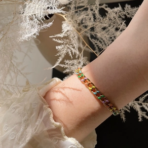 Close-up of gold Cuban link bracelet with colorful drip oil enamel on model's wrist
