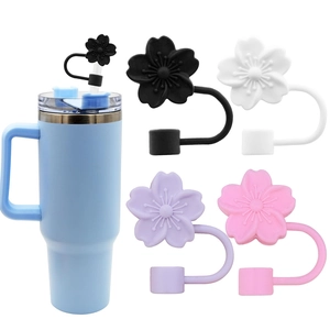 Close-up of silicone floral straw toppers in multiple colors on a blue tumbler