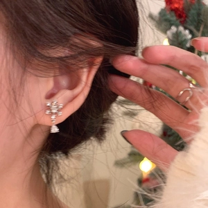 Silver snowflake earrings with zircons shown on a model against festive holiday lights