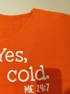 Détail du pull en maille orange à col en V avec imprimé graphique blanc 'Yes, cold. ME 24:7'