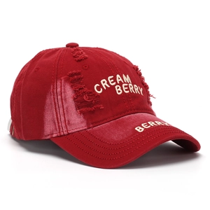 Detailed embroidery of CREAM BERRY logo on distressed dark red cotton baseball cap