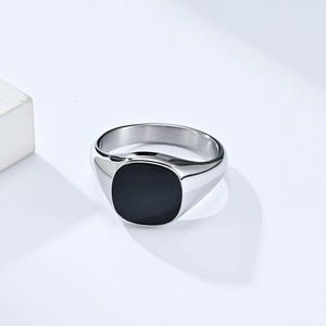 Polished stainless steel signet ring with black enamel inlay on white geometric background