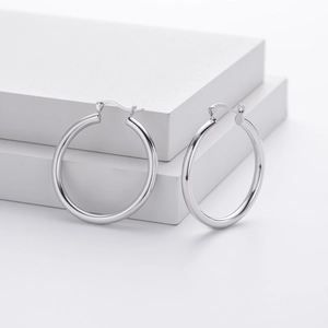 Detailed close-up of large polished silver hoop earrings with high mirror finish