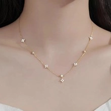 Dettaglio della collana a quadrifoglio dorata con pietre bianche indossata con eleganza