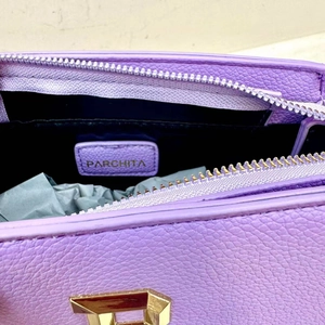 Detail view of purple leather tote bag interior with metal zipper and brand logo