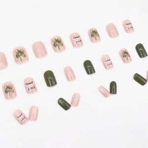 Short round press-on nails set in green and pink with Good Luck clover patterns