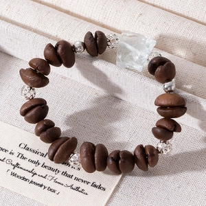 Close-up of coffee bean bracelet with silver beads and irregular raw stone on beige fabric
