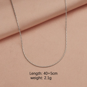 Detailed view of a silver stainless steel cable chain on pink silk fabric background
