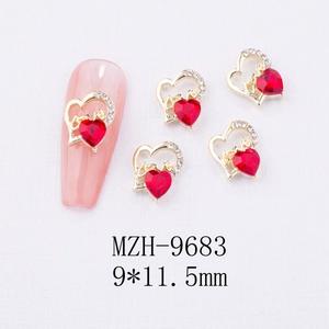 Macro detail of gold alloy heart nail charms with red zircon and Love letter design